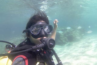 A woman in a scuba gear swimming underwater with the fish