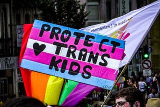 A protest in a street, “Protect trans kids” written on sign