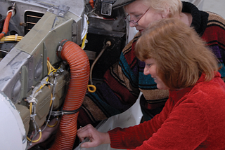 Two women working on an aircraft engine.