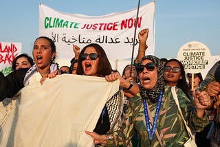 Supporters at a climate justice rally during COP28 holding signage in English/Arabic.