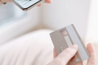 Making a purchase with a credit card on a phone. Photo by Thirdman: https://www.pexels.com/photo/person-holding-a-credit-card-6237886/