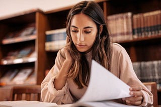 a student in a library looking at papers and books