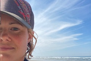 A person who is wearing a purple hat stands by the beach.