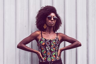 Woman power posing with her head upright and hands on her hips.