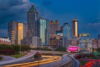 A golden hour view of light trails from freeway traffic in front of the City of Atlanta