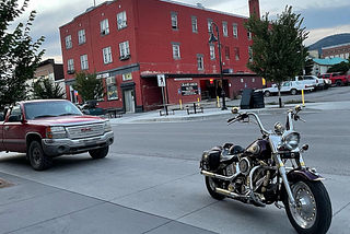 A chromed-up Harley-Davidson motorcycle parked on the street in front of a red brick dive bar.