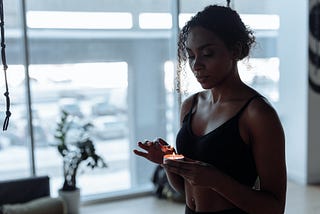 A woman in a black sports bra lighting a candle in a well-lit room