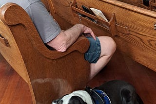 Gray haired man with service dog in church