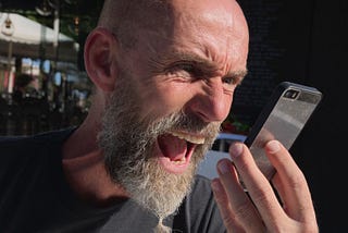 A man shouting angerly at his smartphone.