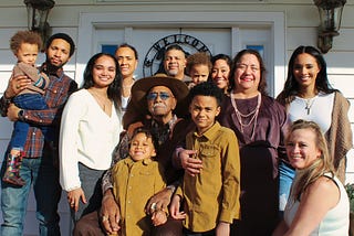 An extended multiracial family poses for a picture in front of white front door