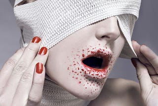 A woman with bandages over her eyes and bloodstained lips