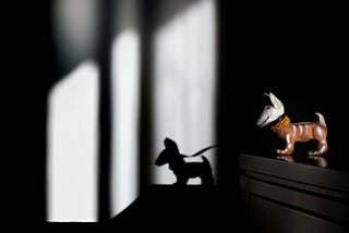 A La Catrina sculpture dog and it’s shadow symbolizes dark and light.