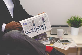 Bottom half of man on chair with business newspaper