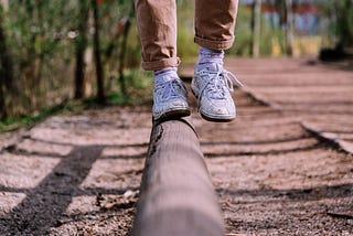 Les pieds d’une personne qui fait l’équilibre sur une poutre (de parcours santé en plein air)