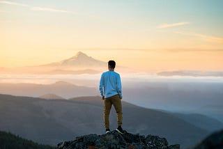 A person standing on a mountain at sunset.