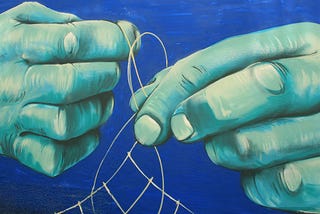 Mural painting of teal hands pulling light thread across a blue background. Mural is on wall in El Cotillo, Fuerteventura. Unknown origin. Seen March 2019