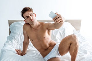 A shirtless man in his underwear taking a photo to sext with someone