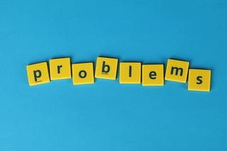 Yellow tiles on a blue background that spell “problems”.