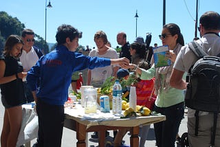 Young kids dealing with a crowd of people around their lemonade stand.