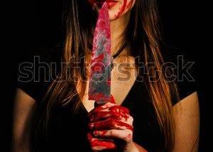 a cute girl in a black dress looking at you lovely but with a blood covered knife and hands.