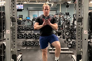 The author, taking a mirror selfie near a powerlifting rack.
