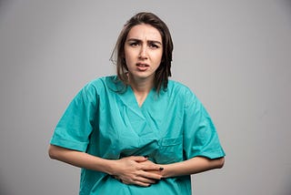 Woman with a worried expression and her hands on abdomen.