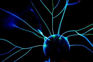 Streaks of bright blue static electricity from a metal ball on a black background