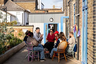 Members of South Norwood Community Kitchen sit in a sunny garden and discuss shared issues.