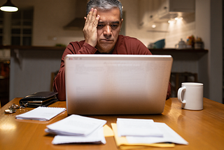 Bereaved man using a laptop on a kitchen table.
