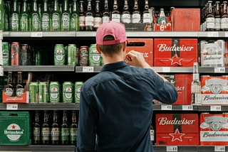 Consumer in front of beer isle, going for the brand of his preference.