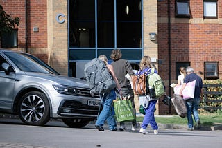 Students moving in with family members helping, carrying items from the car