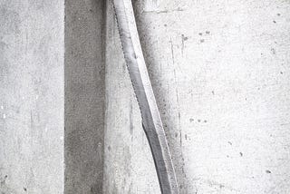 Antique sword leaning against white wall outside