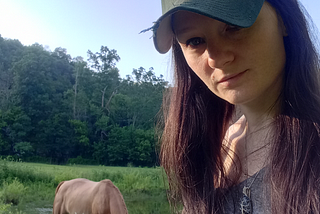 author of the story stands near a horse as it grazes