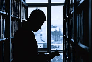An academic readin a book in a library.