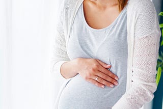 young pregnant woman holding abdomen lovingly