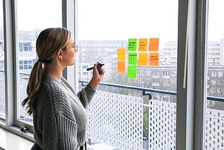 a woman making notes on an office window