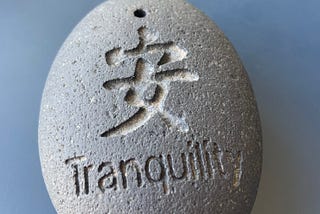 oval stone with the word “Tranquility” and a Chinese character engraved on it.