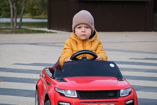 A child is driving a miniature toy car.