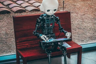 A smart robot reading the digital book sitting on a bench