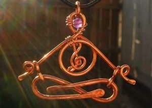 Meditating figure made from copper with a crystal in the head space and a music symbol in the heart space.