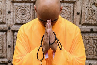 A Buddhist Monk Praying with Prayer Beads