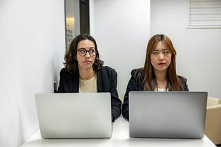 2 ladies sitting side by side at a desk.