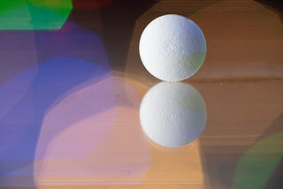Close-up of a reflected pill on a reflective surface. Colorful lights background.