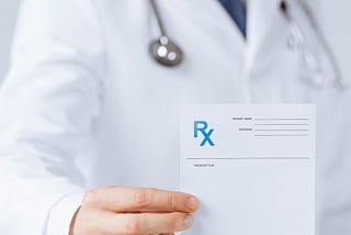 Person in white coat holding prescription