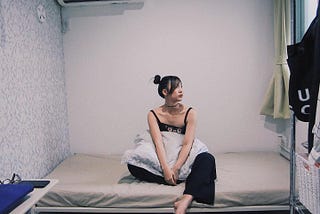 The author Lyn Chen sitting on her bed in her new rented room in Suginami City, Japan