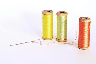 A trio of spools of thread, one yellow, one green and one red