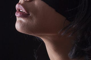 The headshot of an attractive girl, but the upper part of her face is covered by a mask.