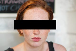 Woman with black box covering her eyes to signify protection of her identity.