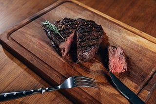 Close up shot of delicious medium rare grilled steak on a cutting board.