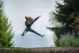 Woman jumping out of celebration on an open trail.